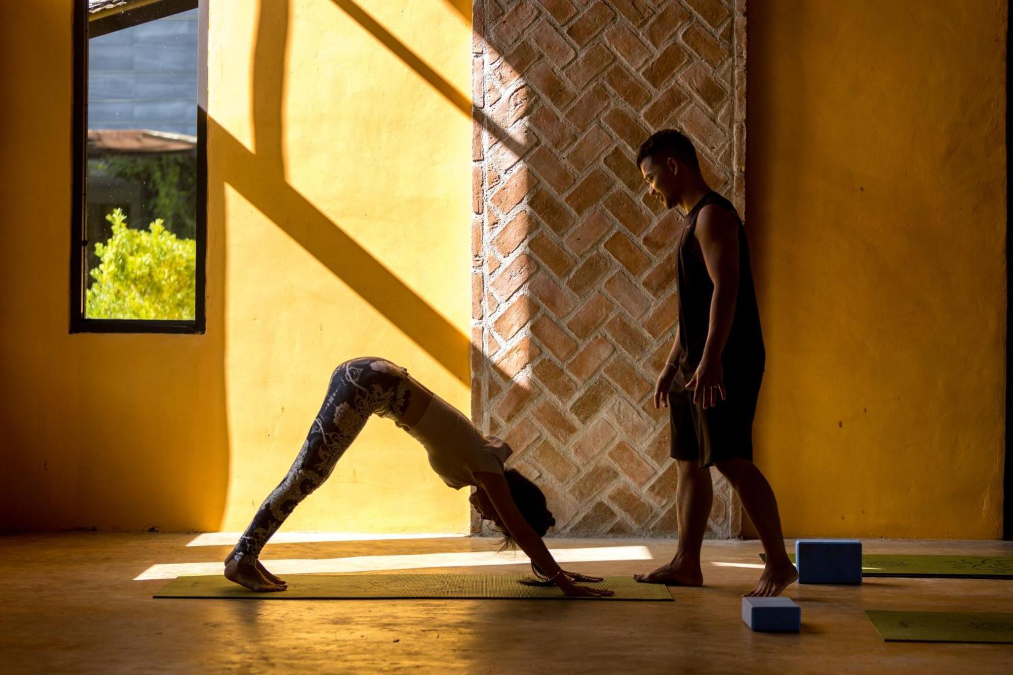 Anana Ecological Resort Krabi - Sha Extra Plus Ao Nang Dış mekan fotoğraf A yoga instructor assists a student with downward-facing dog.